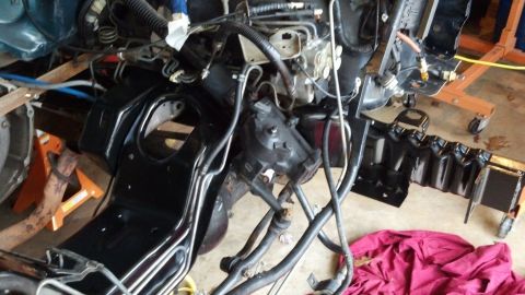 1993 Ford Bronco - The front end of a vehicle is disassembled, showing the frame and engine components supported by jack stands.