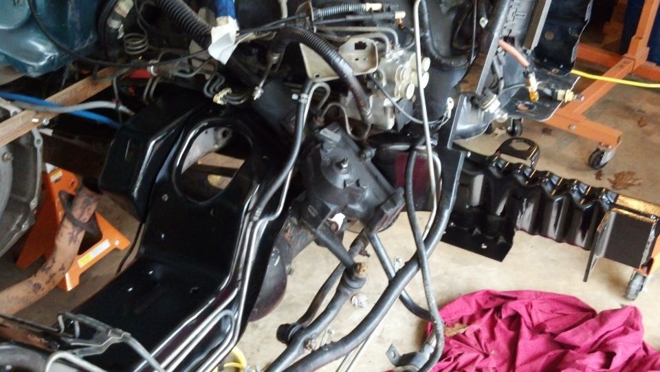 vehicle frame and engine parts on jack stands, looks like it's being worked on