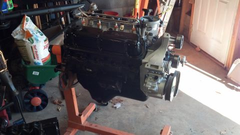 1993 Ford Bronco - Engine on a stand in a garage setting, with gardening equipment nearby.