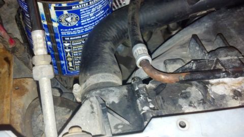 1993 Ford Bronco - A close-up view of engine bay components, including hoses and a coffee can, with visible text on the can.