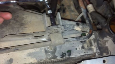 1993 Ford Bronco - A mechanic is using a socket wrench to work on the fan shroud of a vehicle, with green fluid leaking nearby.