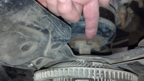 1993 Ford Bronco - A mechanic's hand points to a component of the vehicle's suspension system, with a fan visible below.
