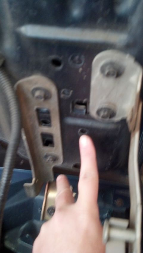 1993 Ford Bronco - A finger points to a metal bracket and bolts within a vehicle's engine bay.