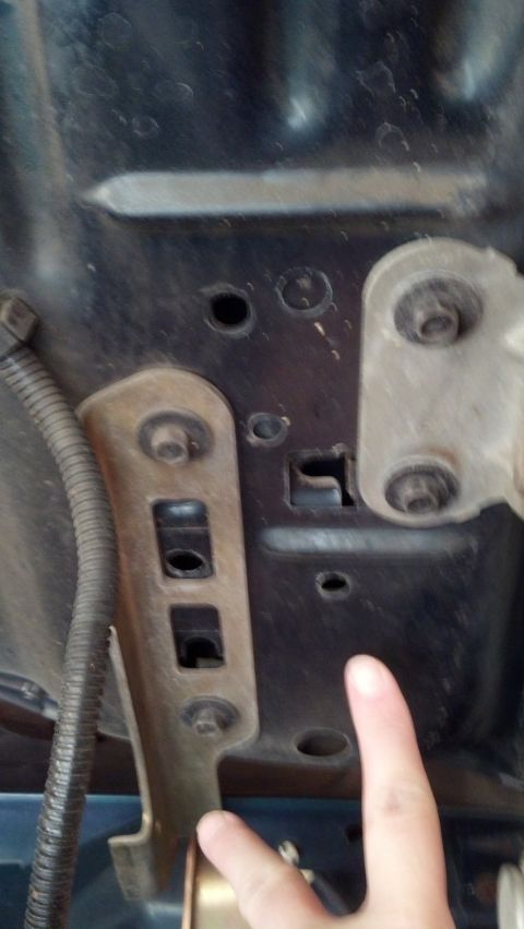 1993 Ford Bronco - Close-up view of the hood latch mechanism, with a finger pointing to a specific area.