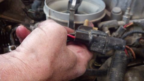 1993 Ford Bronco - A hand disconnects an electrical connector in the engine bay. The Supermotors.net logo is visible in the lower right corner.