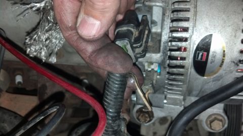 1993 Ford Bronco - Close-up of an alternator with its wiring harness disconnected. A Remy New label is visible on the alternator casing.