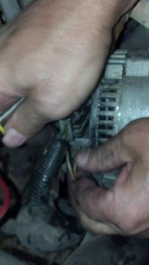 1993 Ford Bronco - Hands are shown working on the wiring of a car's engine, likely an alternator.