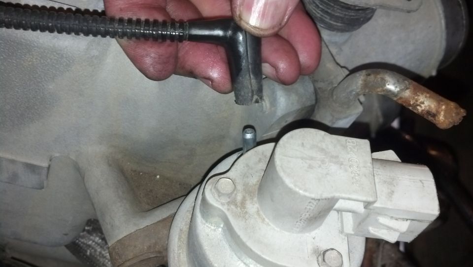 Engine part with disconnected vacuum hose and rusty metal tube