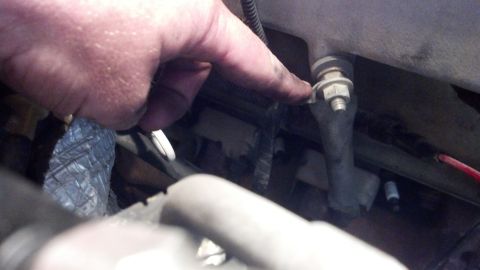 1993 Ford Bronco - Close-up of a hand indicating a specific part within an engine bay.