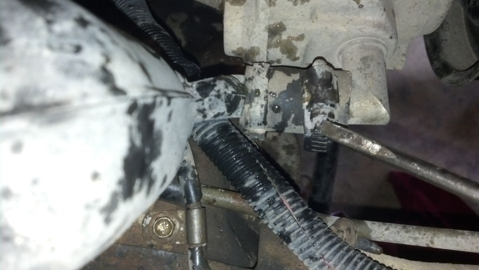Close-up of a grimy engine component with a screwdriver