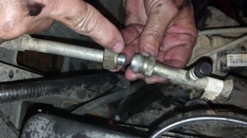 1993 Ford Bronco - Close-up of hands working on an automotive AC line connection, with visible text from SuperMotors.net.