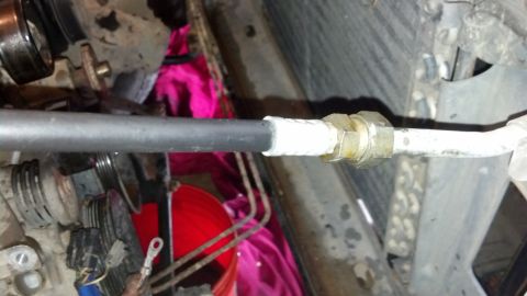 1993 Ford Bronco - A close-up view of a metal hose connection, possibly part of an engine or cooling system, with white tape wrapped around it.