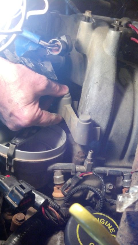 1993 Ford Bronco - Close-up view of an engine bay with a hand interacting with engine components.