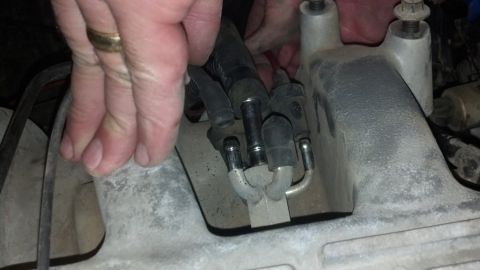 1993 Ford Bronco - Hands connect fuel lines to an engine part, possibly during a tear down or repair.