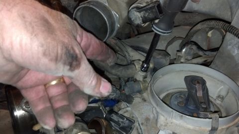 1993 Ford Bronco - A mechanic works on a vehicle's engine, focusing on a sensor replacement.