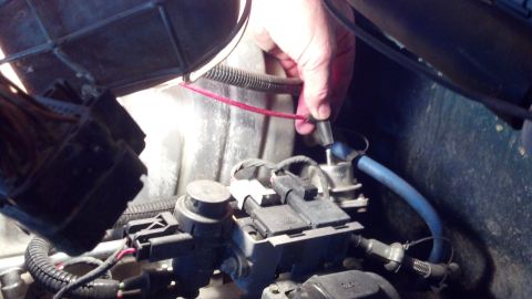 1993 Ford Bronco - Close-up of a hand working on engine components, likely a diagnostic or repair task.