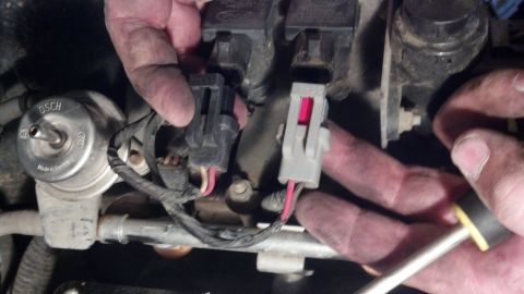 1993 Ford Bronco - Close-up of engine components, including a Bosch-labeled part and electrical connectors, during a tear-down process.