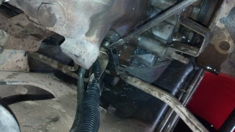 1993 Ford Bronco - This image shows a close-up view of a vehicle's transmission linkage, with some fluid present.