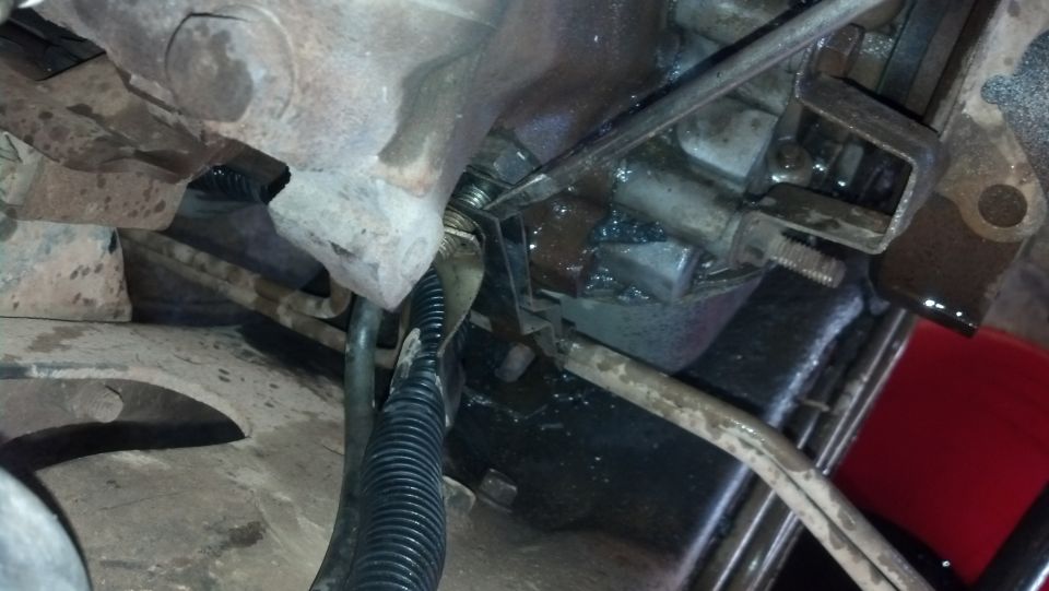 close-up of vehicle transmission linkage with some fluid visible