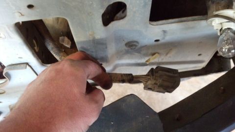 1993 Ford Bronco - A hand disconnects an electrical connector, likely during a tear-down or repair process.
