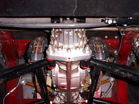 1967 Ford 427 - Close-up view of a racing vehicle's quick change rear end assembly, dual brake calipers and red suspension components.
