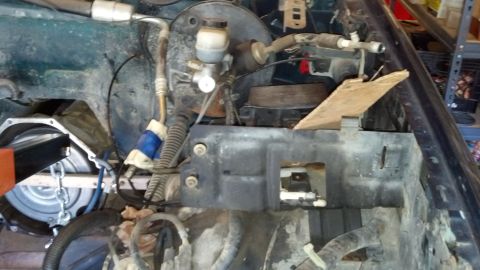 1993 Ford Bronco - Close-up view of a vehicle's engine bay, showing various mechanical parts and hoses during a repair or disassembly process.