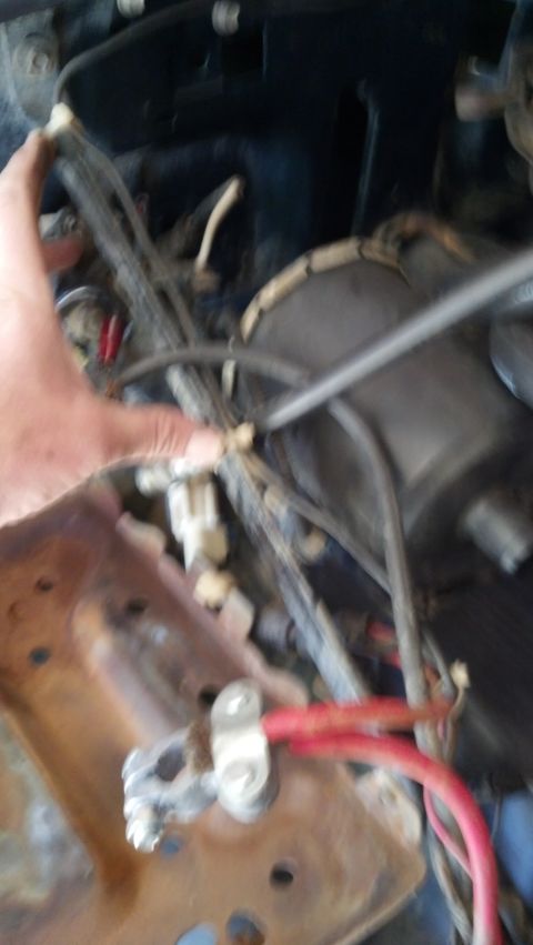 1993 Ford Bronco - A close-up view of the engine bay shows wiring and battery cables, with a hand interacting with a connector.