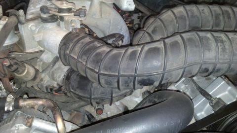 1993 Ford Bronco - Close-up view of the engine's air intake system, showing rubber hoses and metal components.