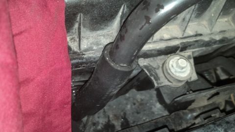 1993 Ford Bronco - Close-up view of an engine hose and its mounting bracket, partially covered by a red cloth.