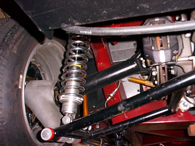 Coilover shock and tubular A-arms on red tube-frame roadster front suspension