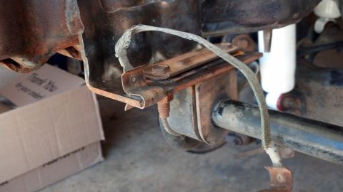 1993 Ford Bronco - Close-up of a vehicle's rear axle assembly, showing rust and a white shock absorber.