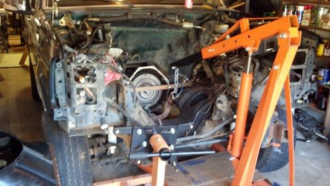 1993 Ford Bronco - The engine bay of a 1993 Ford Bronco is shown with the transmission removed and an engine hoist in place.