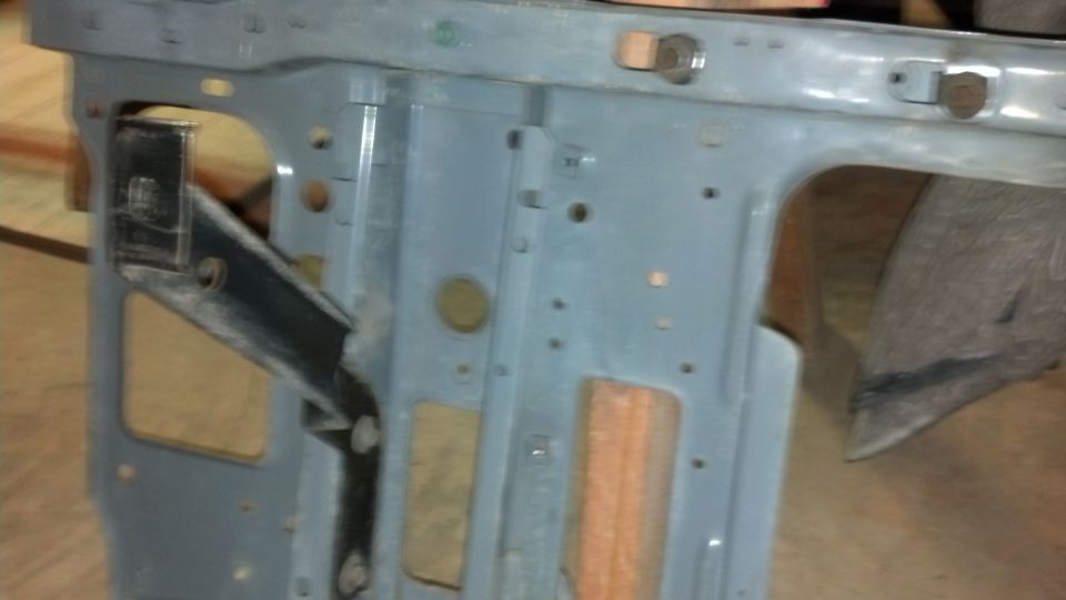 Close-up of a gray metal vehicle frame section with various holes and brackets