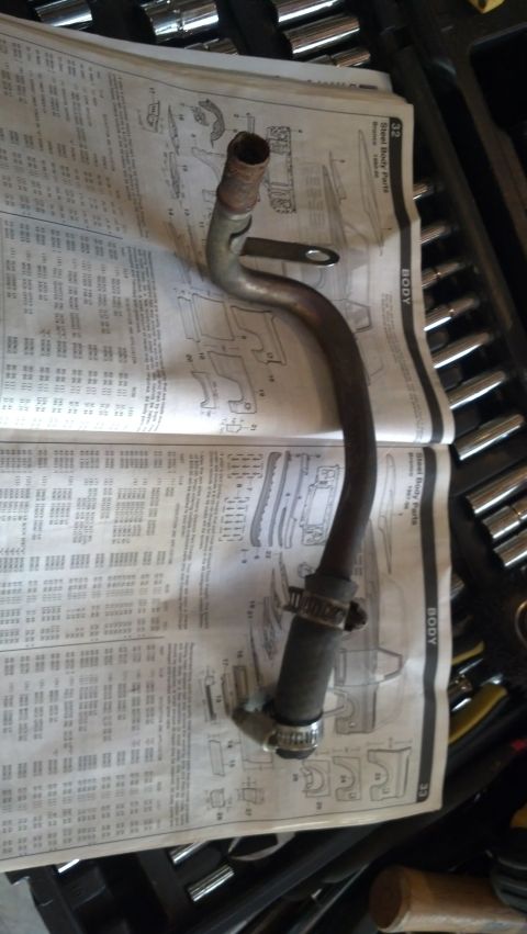1993 Ford Bronco - A metal pipe with a rubber hose and clamps lies on a page of diagrams.