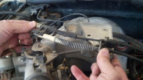 1993 Ford Bronco - Hands working on a cable assembly in the engine bay, likely during a repair or maintenance.