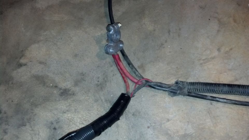 Close-up of automotive wiring harness with red and black wires connected to a metal terminal
