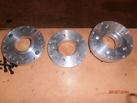 1996 Ford Bronco - Three aluminum wheel spacers and bolts are laid out on a wooden surface.