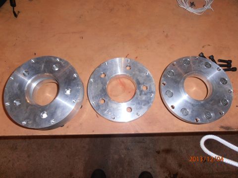 1996 Ford Bronco - Three metal wheel spacers are laid out on a wooden surface, with bolts visible on the right.