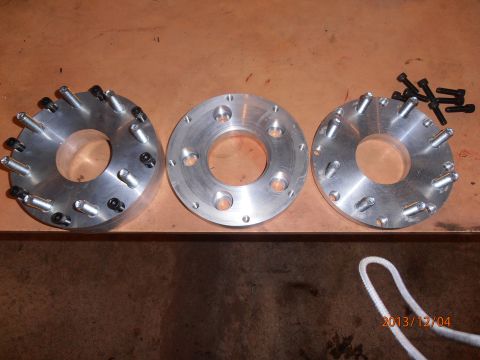 1996 Ford Bronco - Three metal wheel spacers with bolts are laid out on a wooden surface, with a date stamp and website visible in the lower right corner.