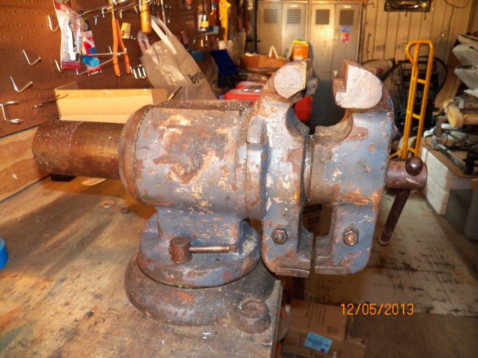 Bench vise on a workbench, showing rust and wear