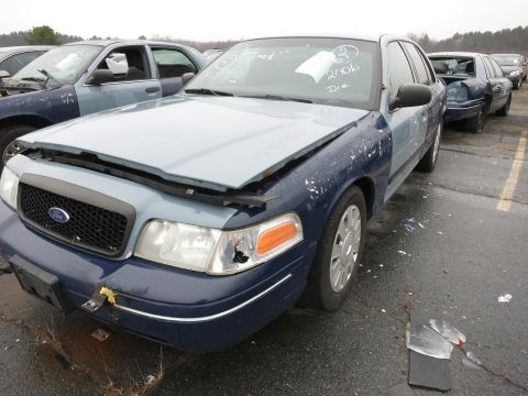 1991 Ford LTD Crown Victoria - A two-tone Ford Crown Victoria sits in a junkyard with other vehicles visible in the background.
