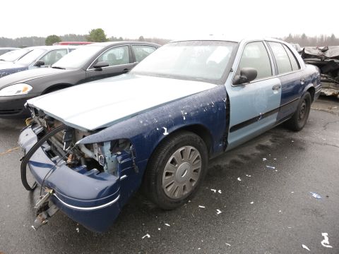 1991 Ford LTD Crown Victoria - A damaged Ford Crown Victoria sits in a lot with other vehicles under an overcast sky.