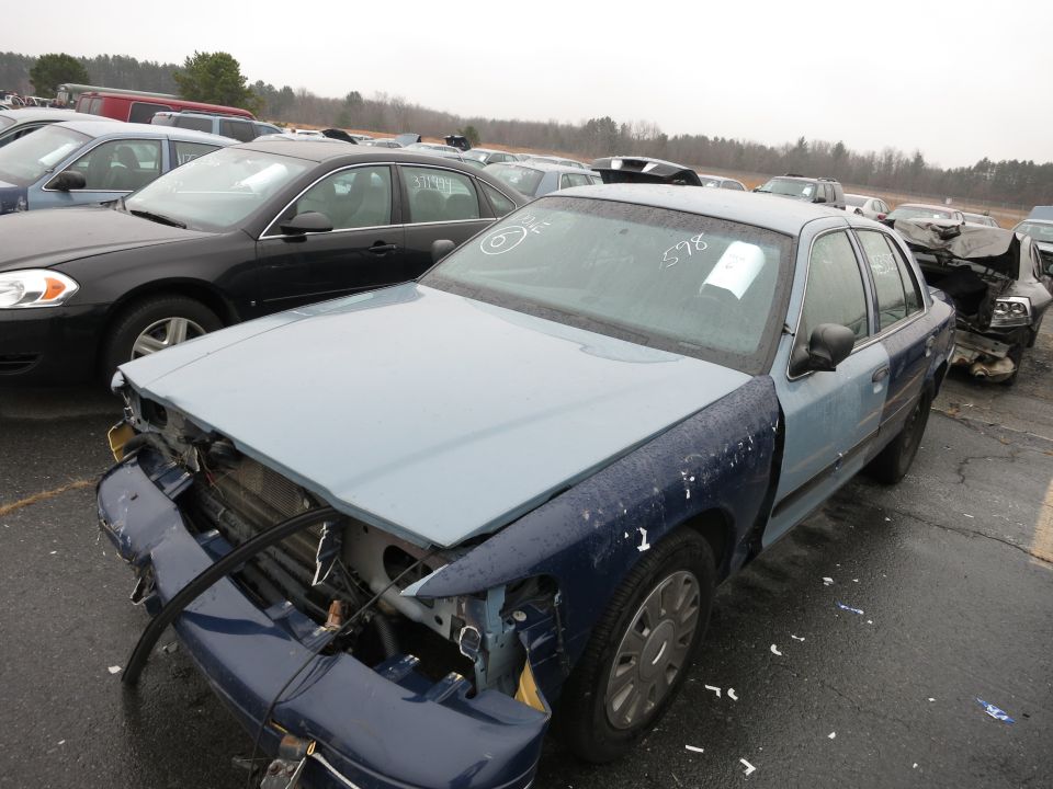 Blue and light blue sedan with damaged front end and visible VIN tag on windshield
