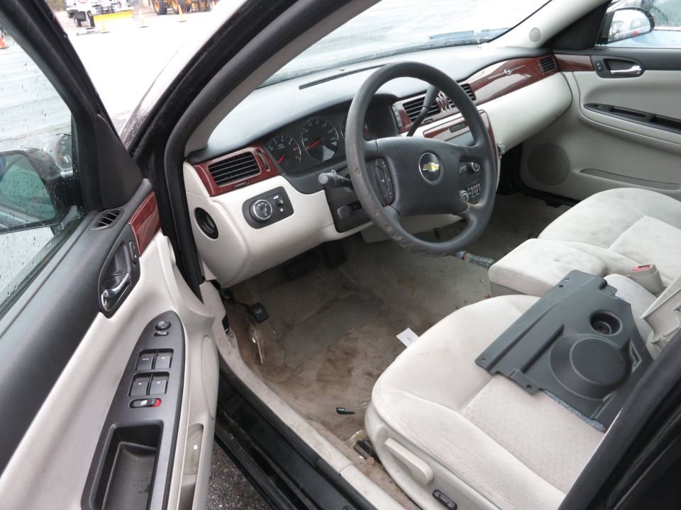 Car interior with tan seats, dashboard, and steering wheel. A black plastic panel rests on the passenger seat
