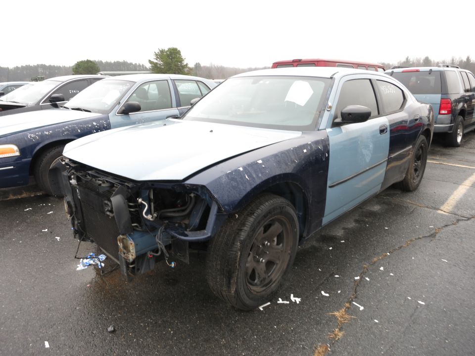 Two-tone blue sedan with missing front bumper and grille, parked next to other vehicles