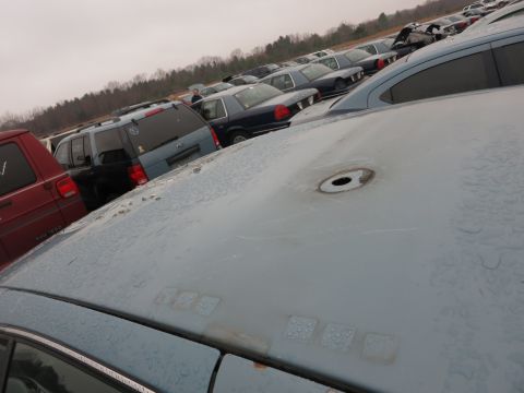 1991 Ford LTD Crown Victoria - A light blue sedan sits in a junkyard with other vehicles under an overcast sky.