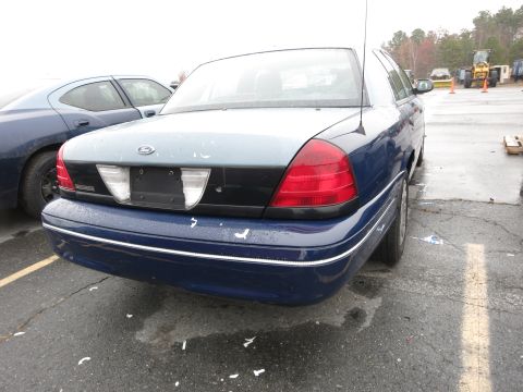 1991 Ford LTD Crown Victoria - A blue Ford Crown Victoria is parked next to another vehicle, with construction equipment visible in the background.