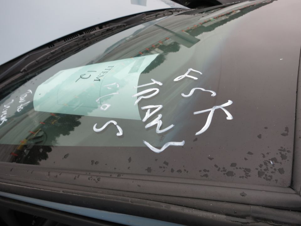 Windshield with white writing and a light blue paper tag