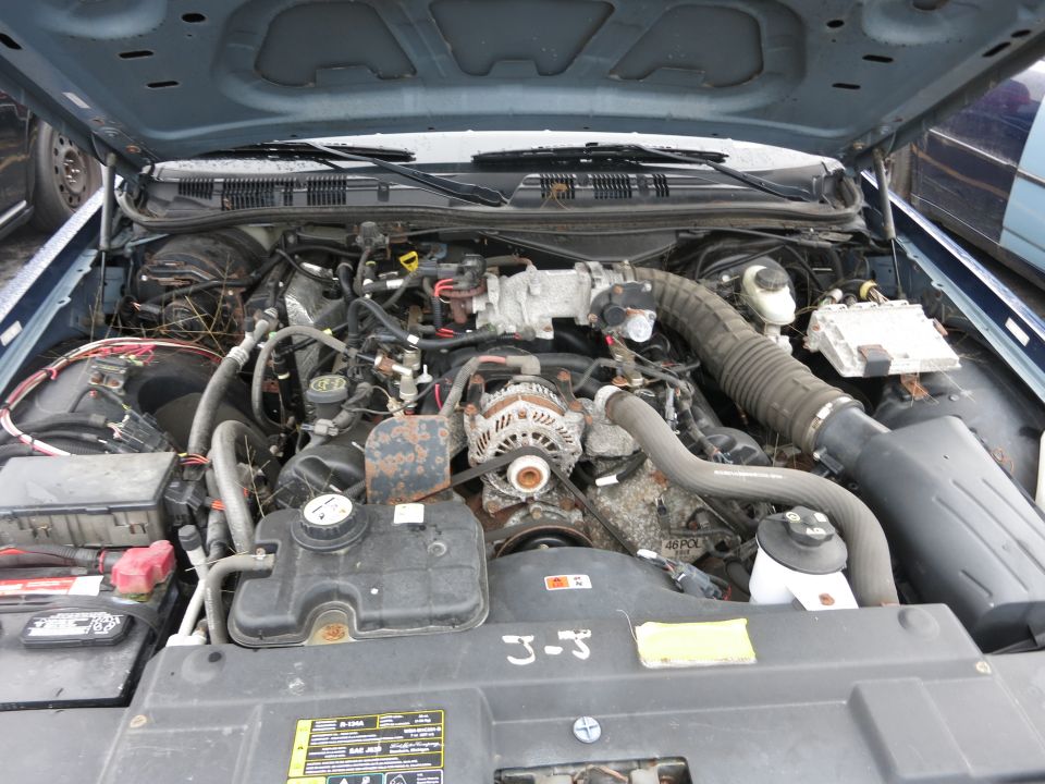 Engine bay with visible V8 engine components and battery