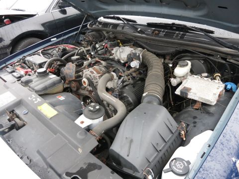 1991 Ford LTD Crown Victoria - Engine bay of a 1991 Ford Crown Victoria LTD, showing various components and another vehicle nearby.
